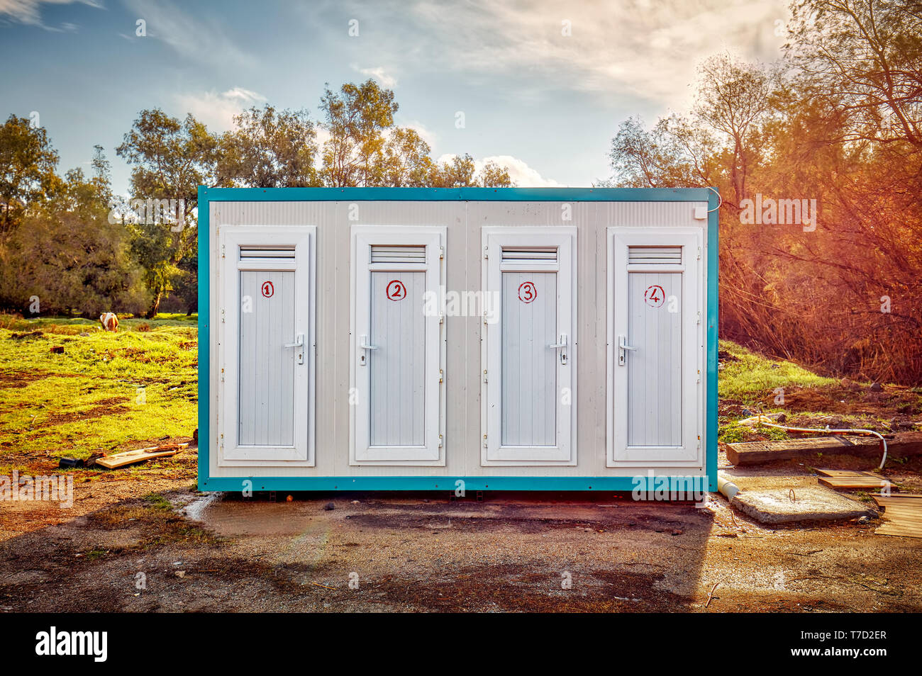 Prefabricated portable cabin with four numbered doors on a meadow field in the forest Stock Photo