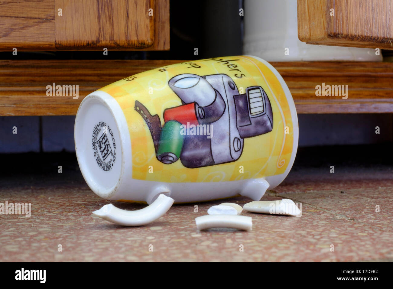 photographers coffee mug laying on tiled floor with broken handle after falling out of cupboard concept lack of focus Stock Photo
