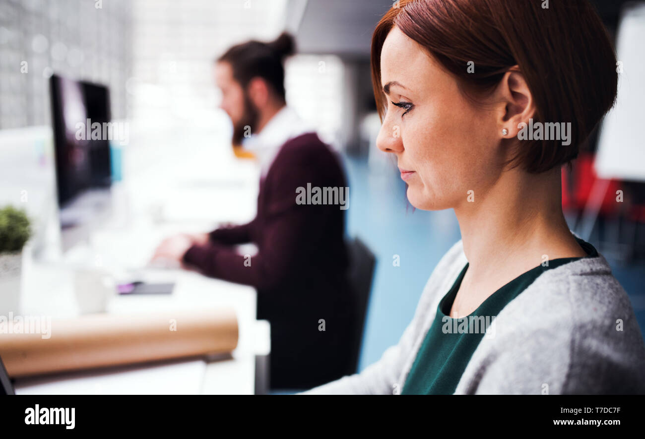 Two young business people working in office, using computer Stock Photo ...