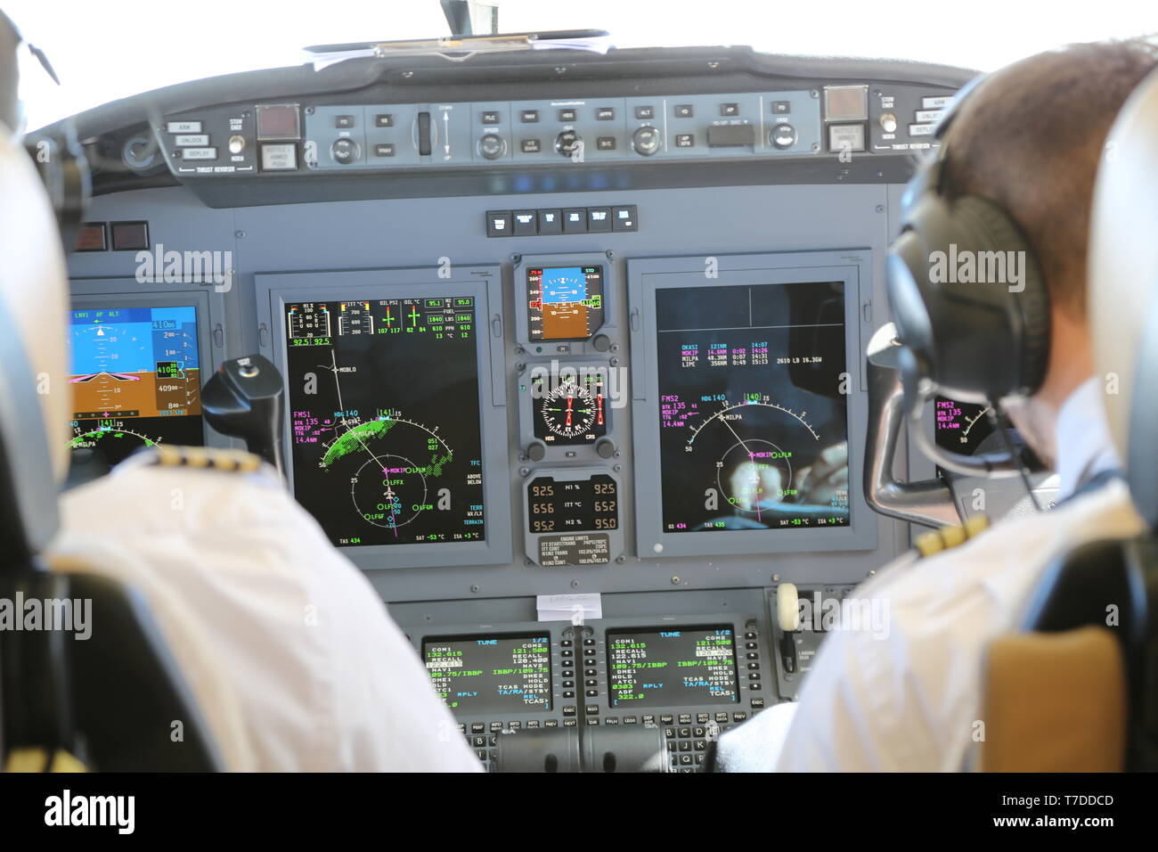 Flight deck of a Cessna Citation XL aircraft with the back of the two pilots and instrumentation in view. Stock Photo