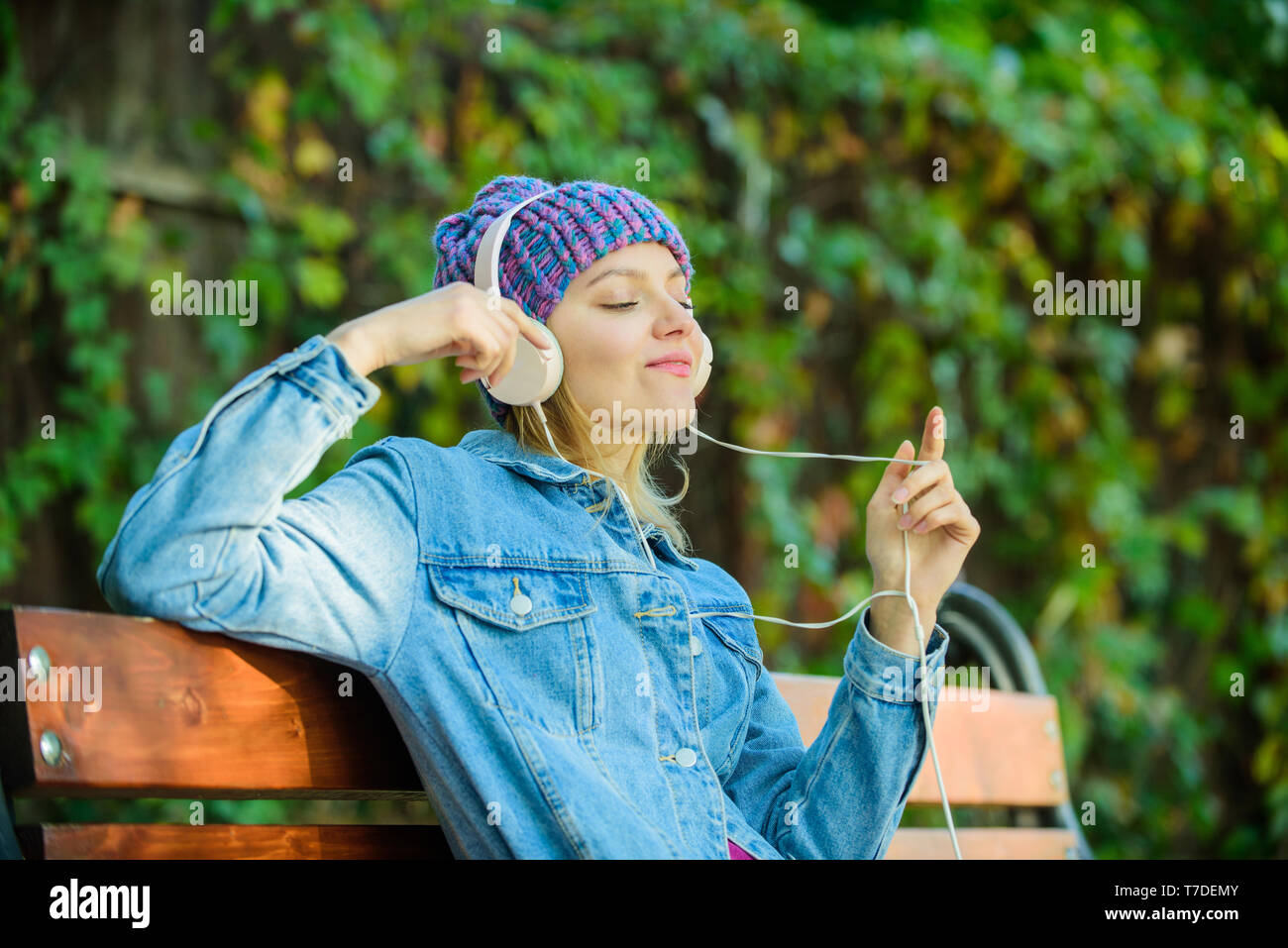 Feeling awesome. Cool funky girl enjoy music in headphones outdoor. Girl  listen music in park. Melody sound and mp3. Music fan concept. Headphones  must have modern gadget. Enjoy powerful sound Stock Photo -