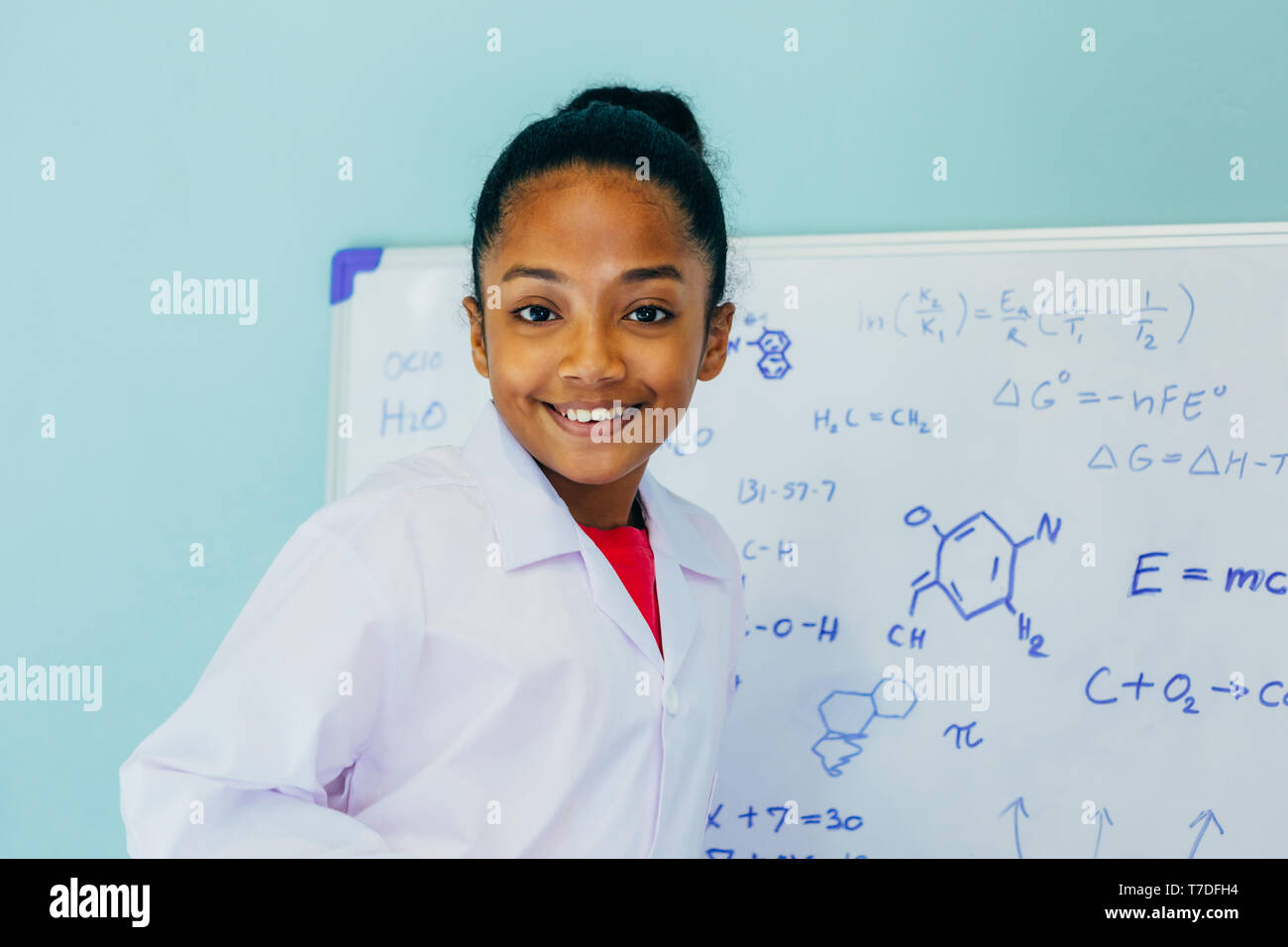 African American girl in lab coat drawing mathematic and science ...