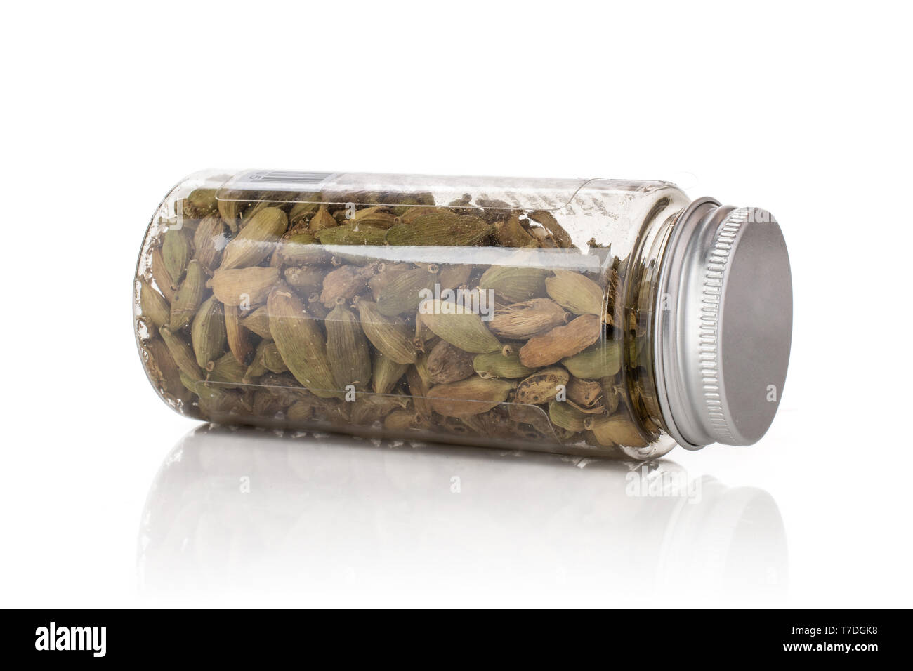 Lot of whole true cardamom pod lying on its side in a plastic bottle isolated on white background Stock Photo