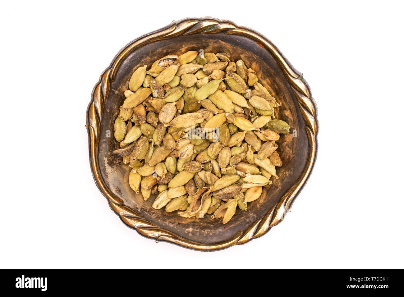 Lot of whole true cardamom pod in old iron bowl flatlay isolated on white background Stock Photo