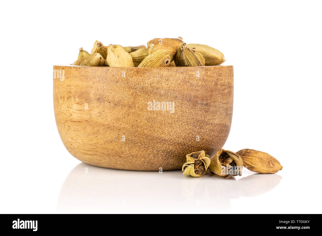 Lot of whole true cardamom pod near and in a wooden bowl isolated on white background Stock Photo