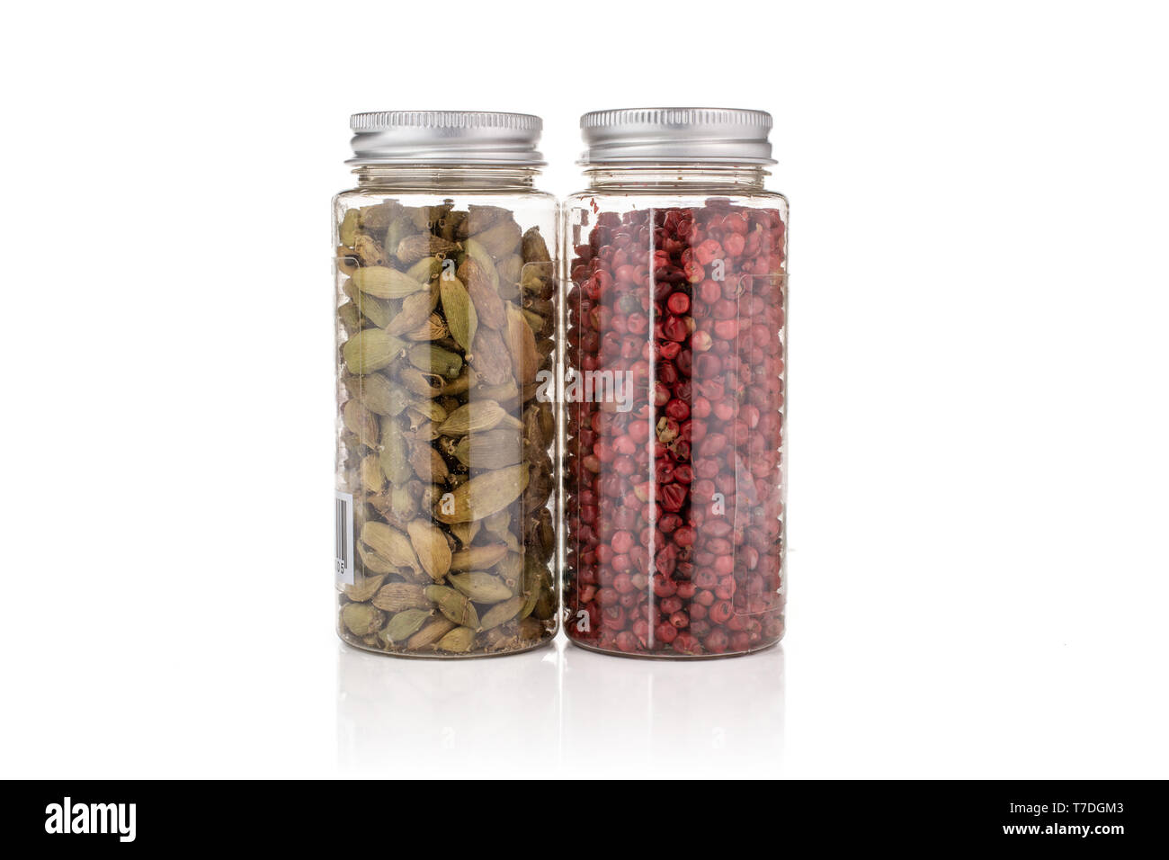 Lot of whole true cardamom pod and peruvian pink pepper in a plastic bottle isolated on white background Stock Photo