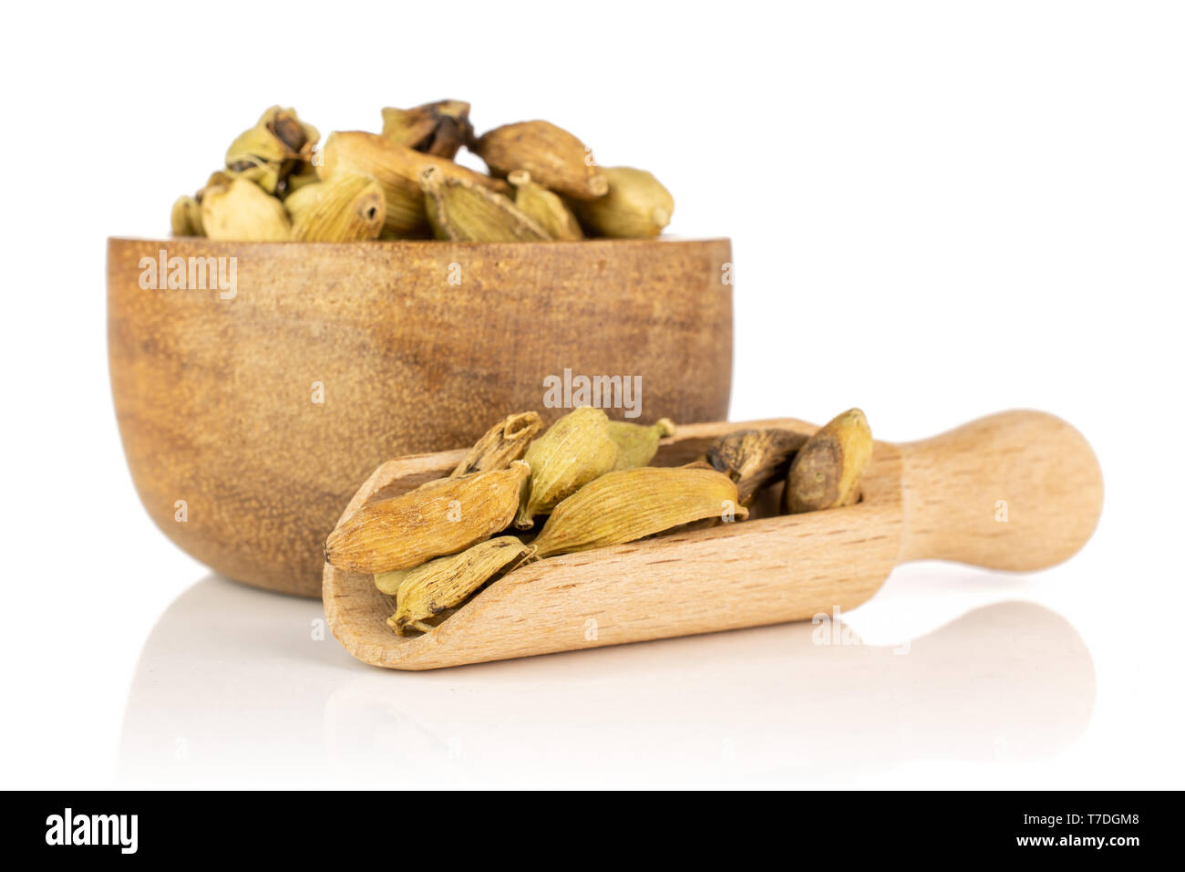 Lot of whole true cardamom pod in a wooden bowl with wooden scoop isolated on white background Stock Photo