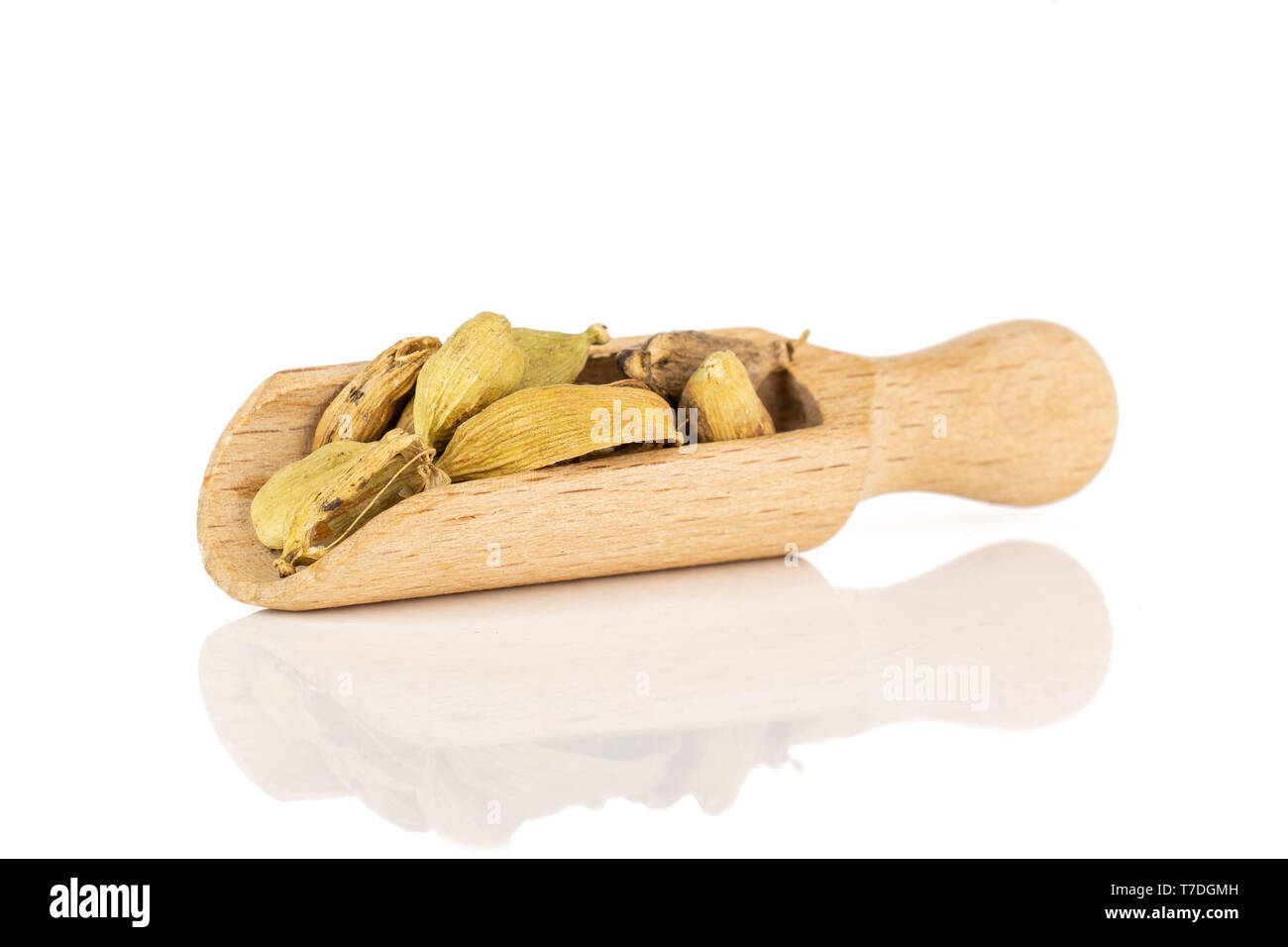 Lot of whole true cardamom pod lot of whole true cardamom pods in a wooden scoop isolated on white background with wooden scoop isolated on white back Stock Photo