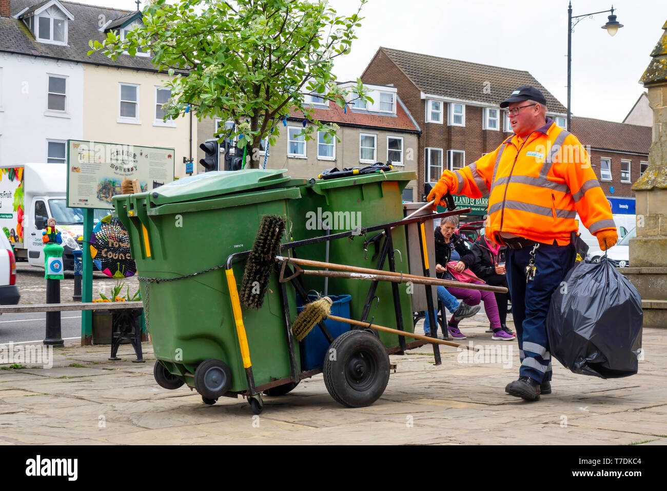 Street sweeper with his equipment hand cart clearing litter bins in Thirsk Market Place Stock Photo