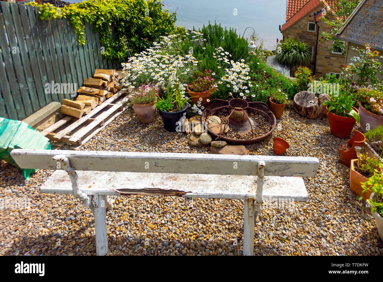 A typical charming small garden in a holiday cottage with a bench seat overlooking the sea in Runswick Bay North Yorkshire Stock Photo