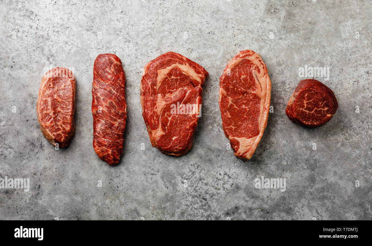 Variety of Raw Black Angus Prime meat steaks Top Blade, Denver, Rib Eye, Striploin, Tenderloin fillet Mignon on gray background Stock Photo