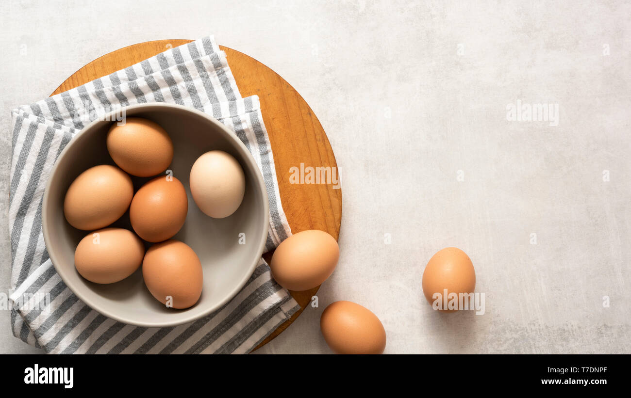 Brown and white eggs in a bowl on a textured grey background with