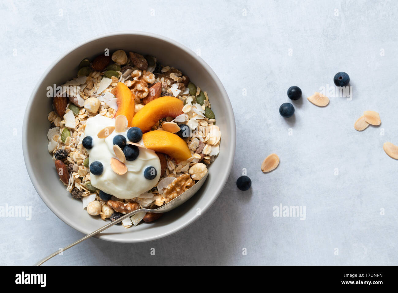 Bowl of homemade muesli with sliced peaches, yoghurt and blueberries. Stock Photo