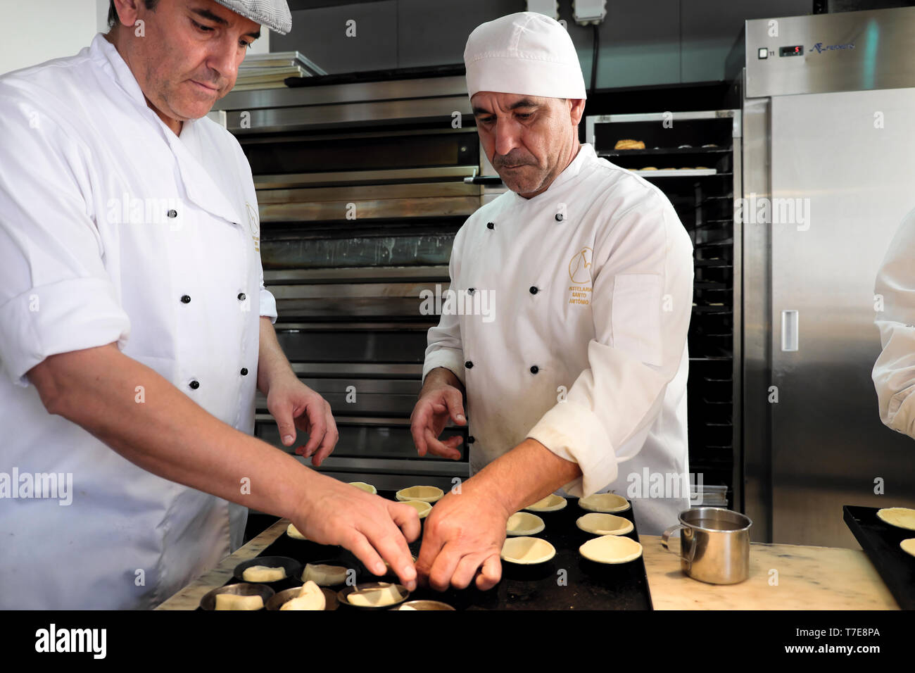 Two male employees working making pastry cases for traditional Pasteis de Nata Portuguese tarts