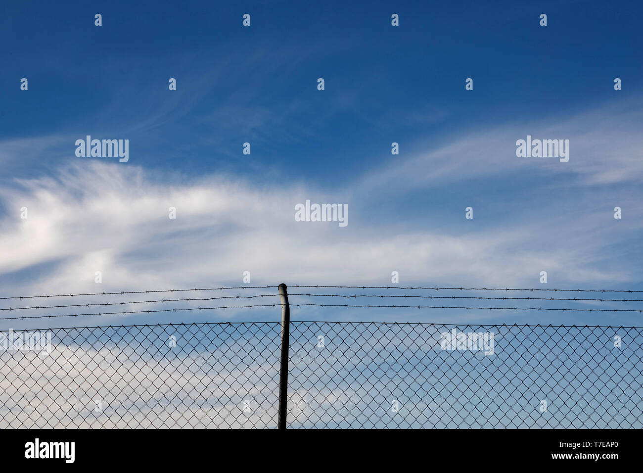 Wire fence with a blue sky with clouds of background Stock Photo - Alamy