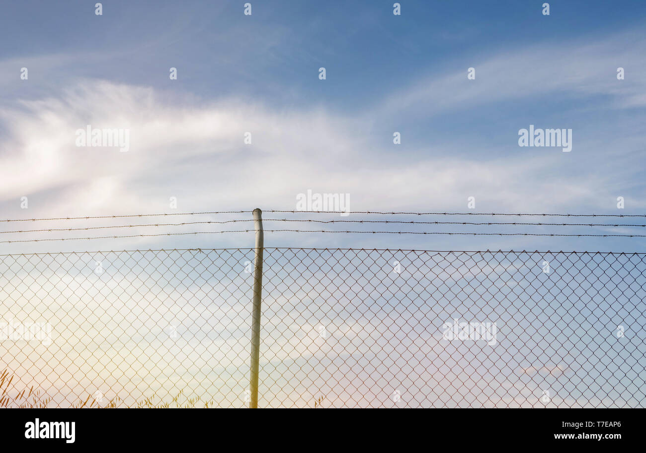 Wire fence with a blue sky with clouds of background Stock Photo - Alamy