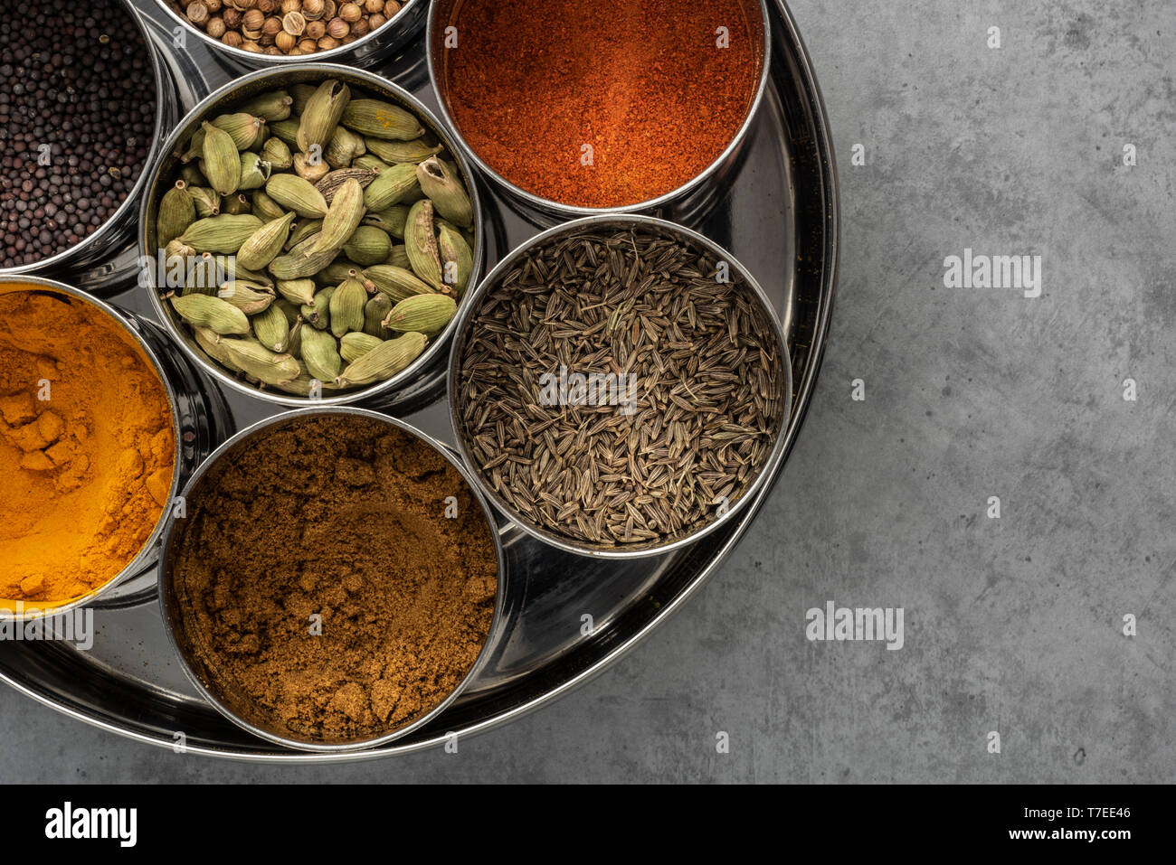 Indian Spice Tin (masala dabba) on cement background seen from above. Stock Photo