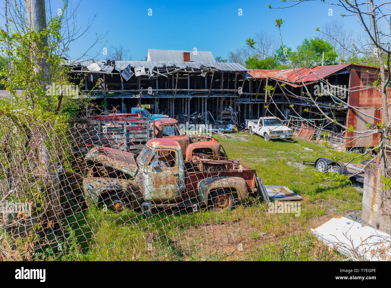 LIMESTONE, TN, USA-4/27/19:  A fenced yard containing junked antique trucks and cars, and a dilapidated building. Stock Photo