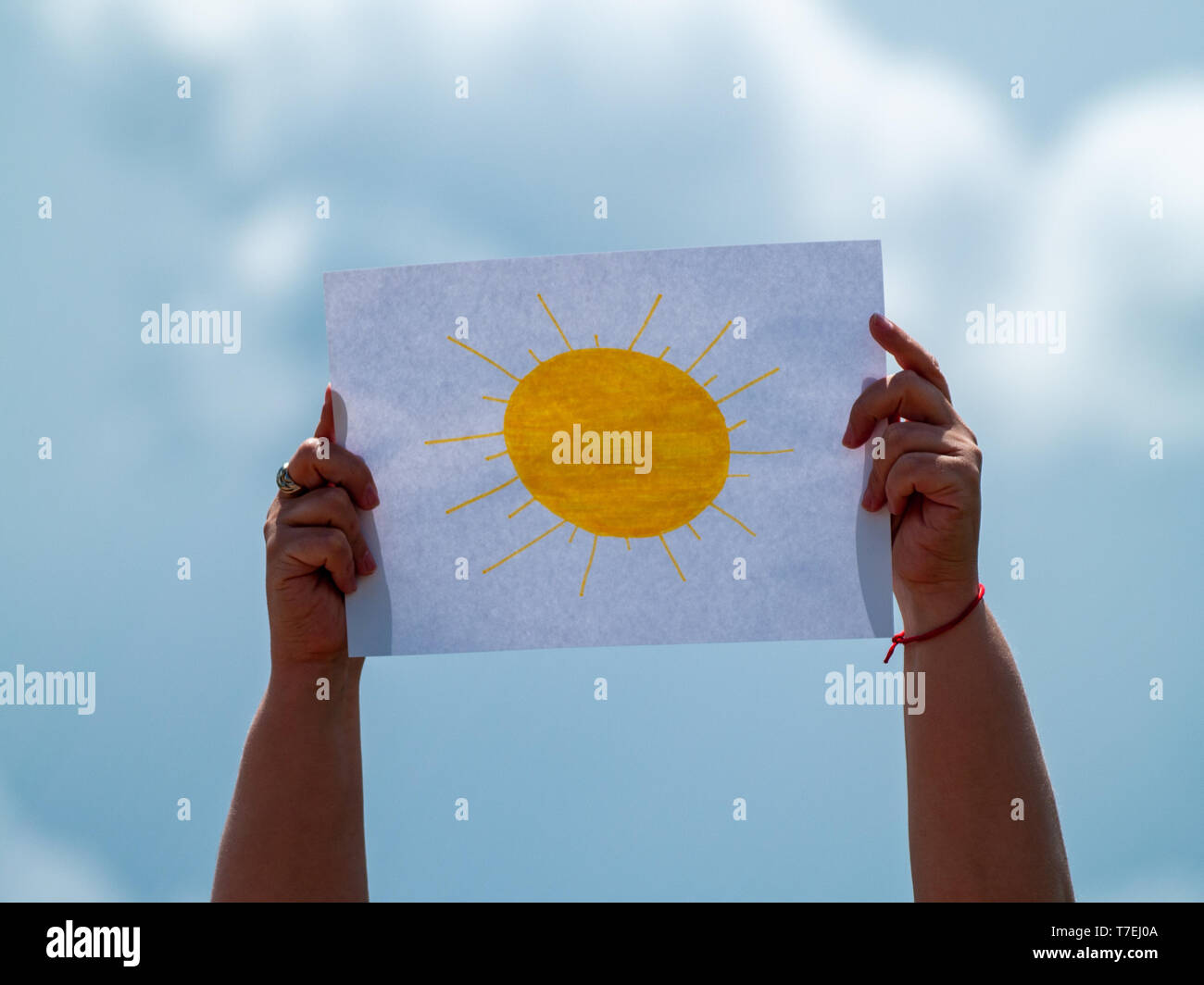 A person with a drawing of the sun on a paper in his hand on a stormy day. Concept of optimism Stock Photo