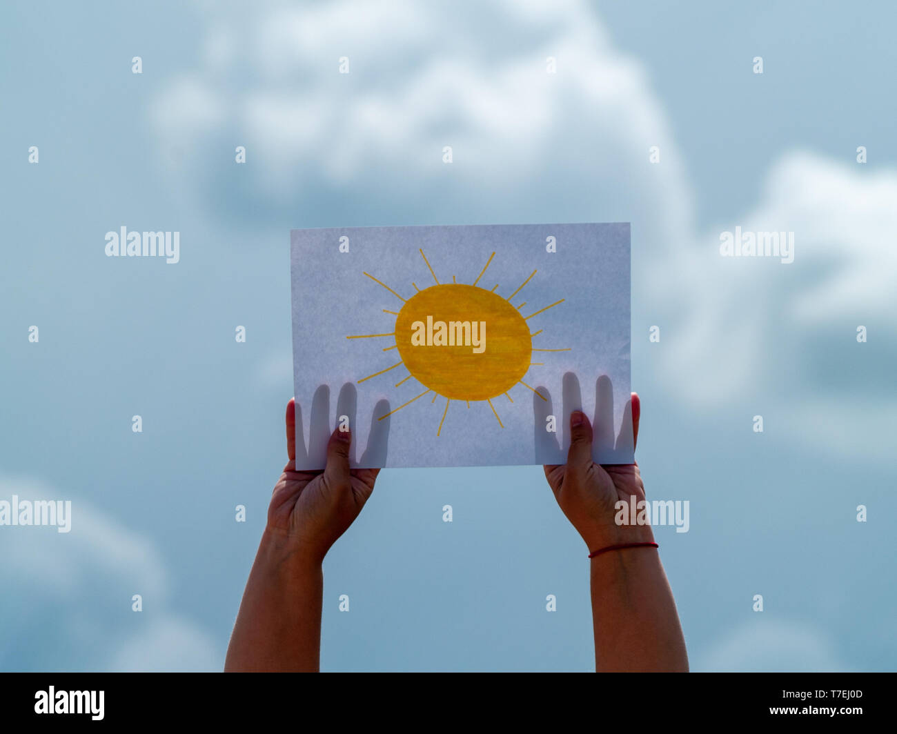 A person with a drawing of the sun on a paper in his hand on a stormy day. Concept of optimism Stock Photo