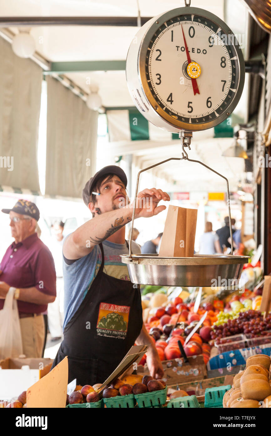 Man vendor weighing produce with a scale at Pike Place Market, Seattle