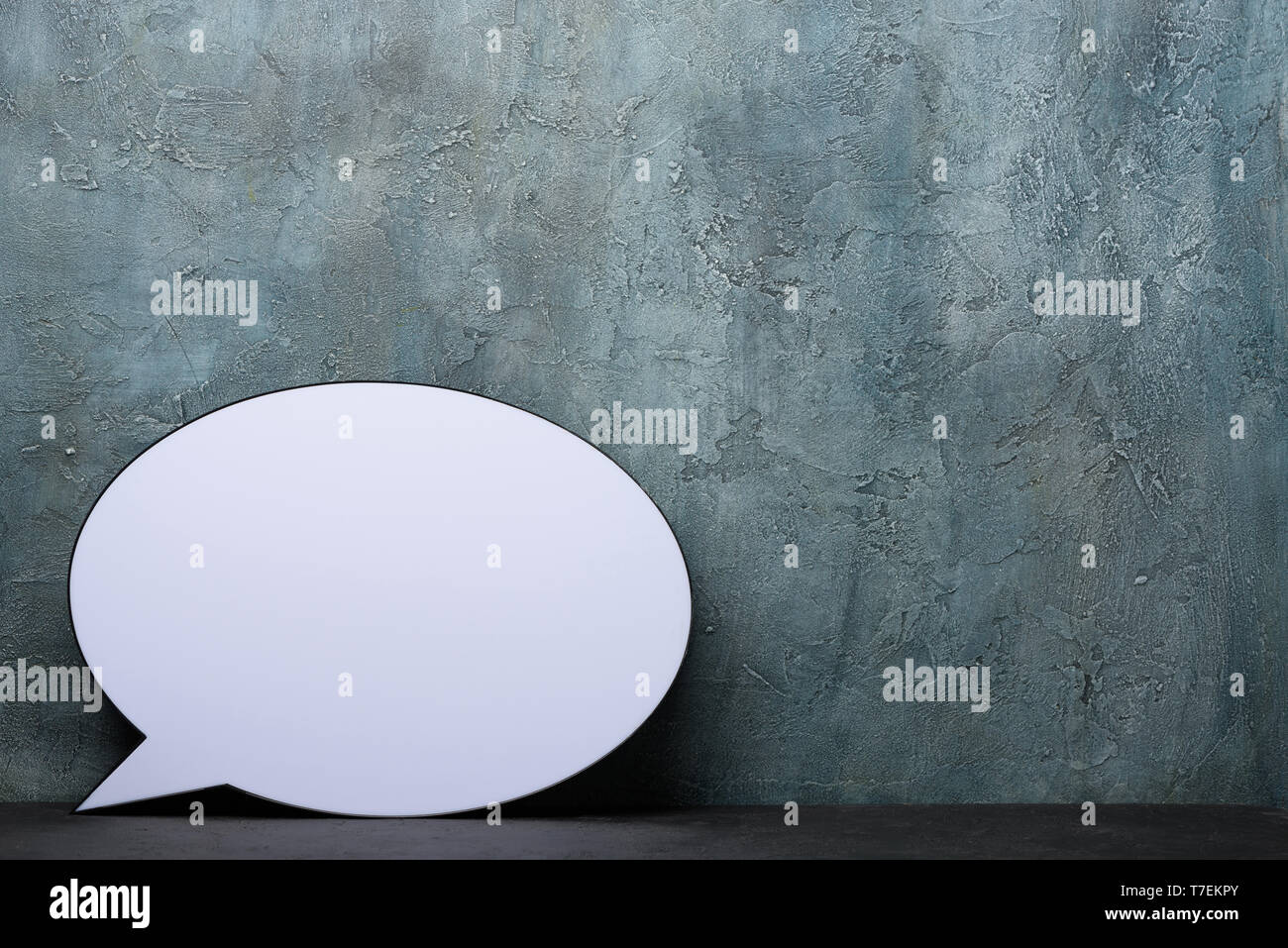 Speech Bubble lightbox on desk. Plastic light box in form of chat message icon with rustic background and copy space. Stock Photo