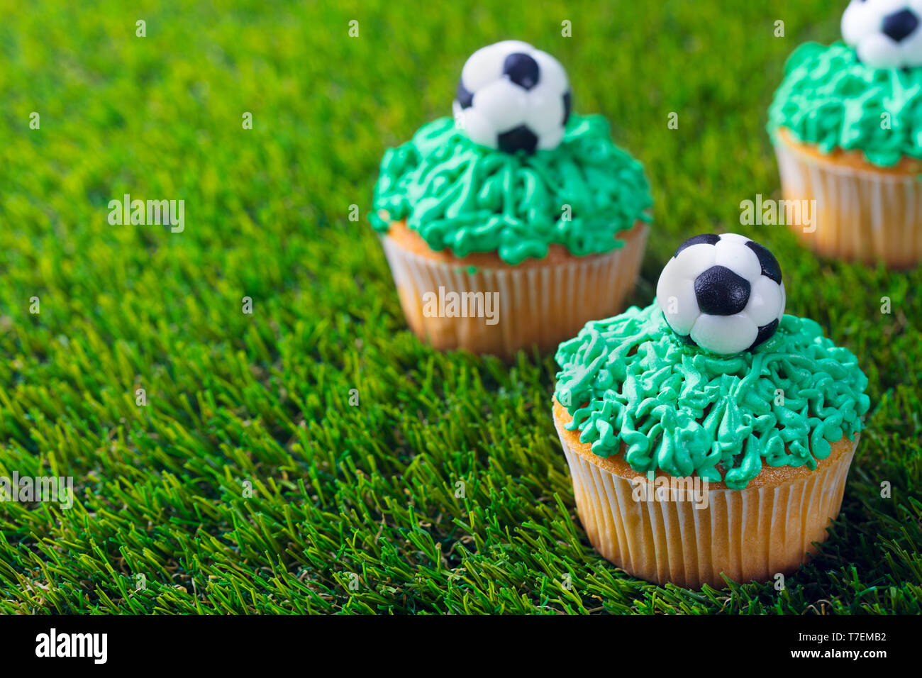 Football party, birthday decorated cupcake on green grass background. Copy space. Stock Photo
