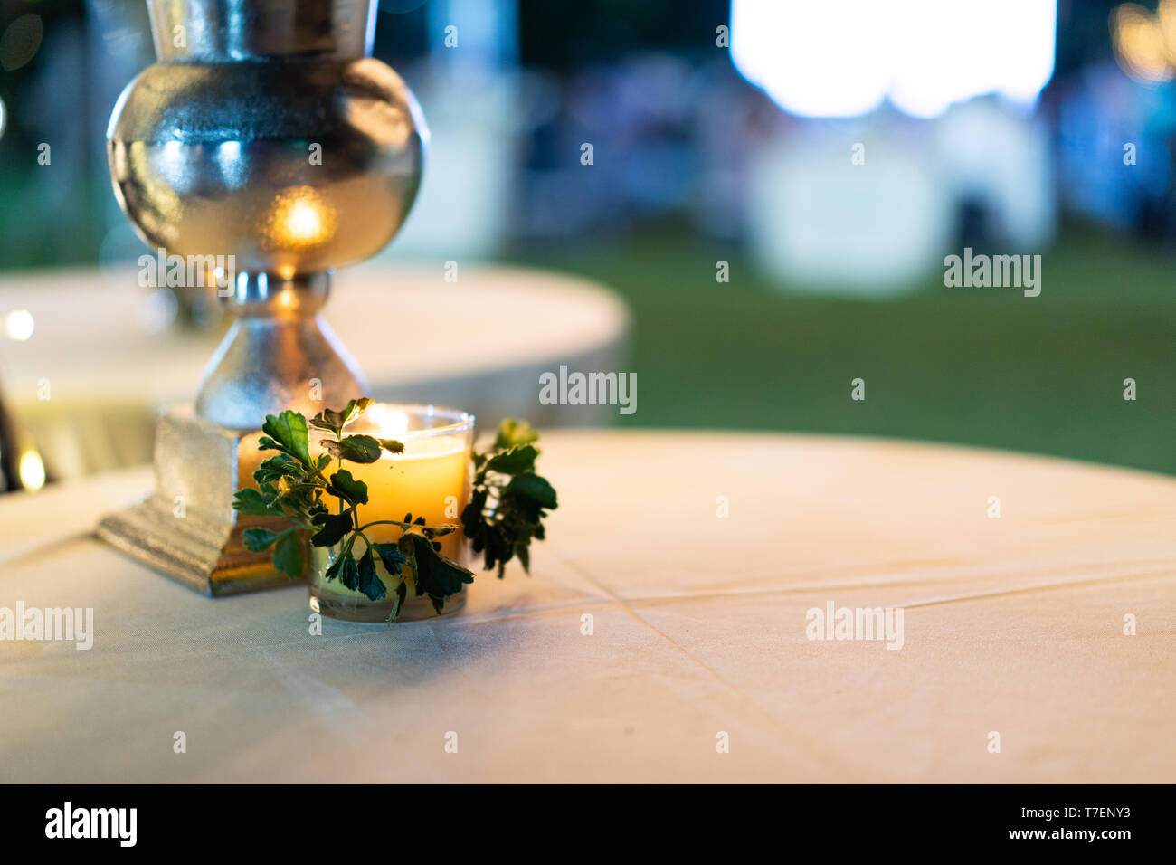 Little cozy candle on the white circle table with blur background. Stock Photo