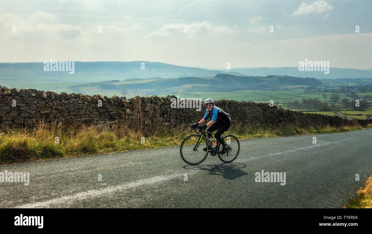Female cyclist nearing the top of Côte de Barden Moor, one of the famous Tour de Yorkshire steep hill climbs. Yorkshire Dales Stock Photo
