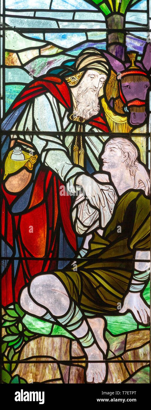 Stained glass window church of Saint Mary, Martlesham, Suffolk, England, UK by Walter J Pearce in Arts and Craft style, 1903 - The Good Samaritan Stock Photo