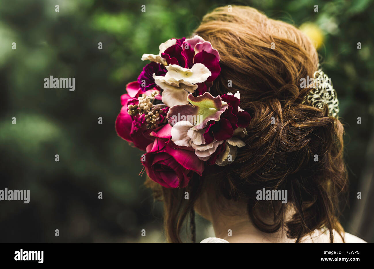 Hairstyle with colorful flowers. Beautiful hair decorated with flowers. Isolated on green background. Hair care concept. Backside view Stock Photo