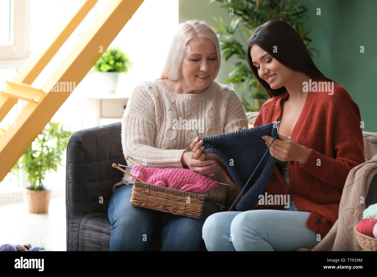 Young and mature women with knitting yarn sitting on sofa indoors Stock ...