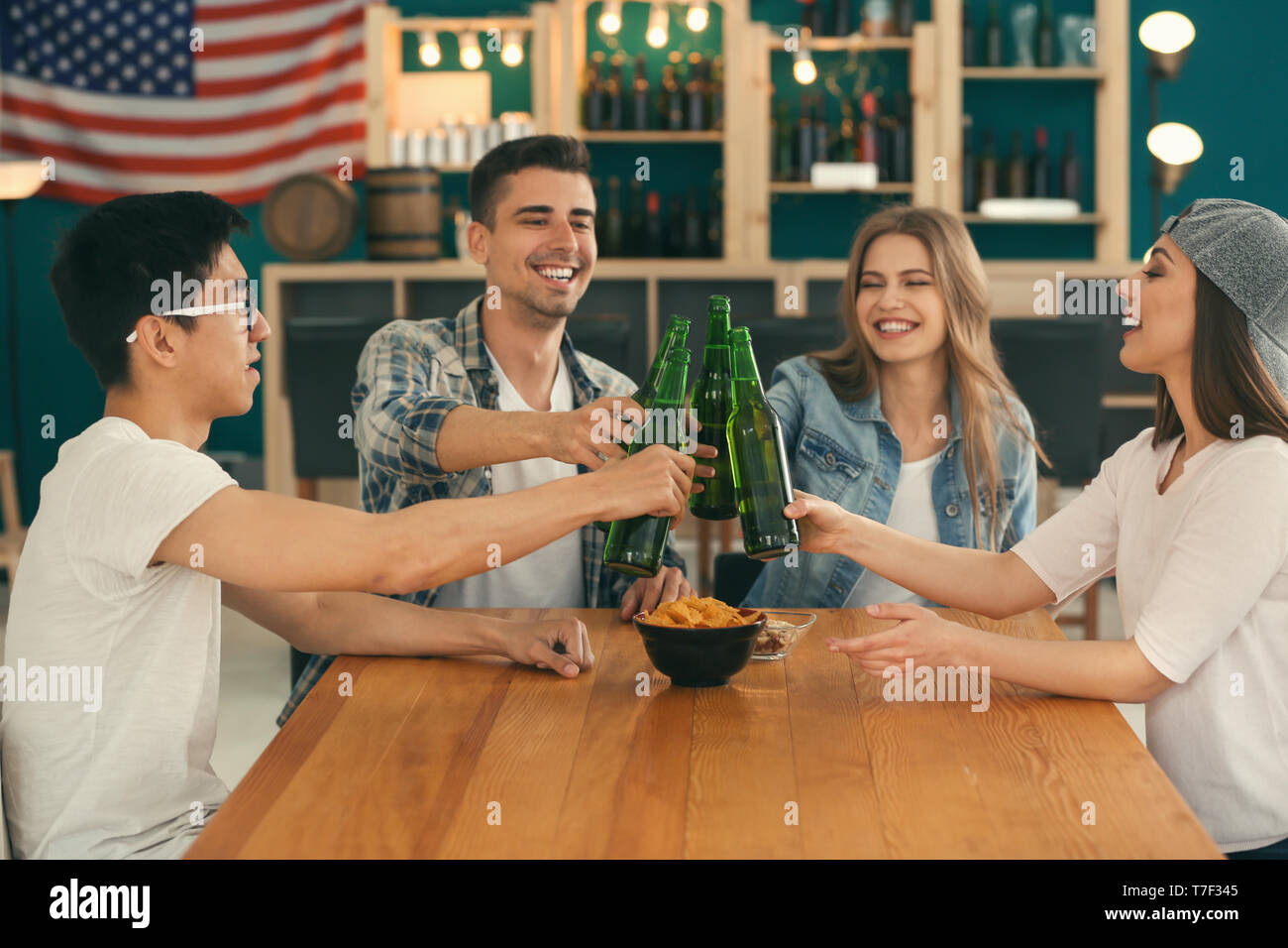 Group of cheerful friends drinking beer in bar Stock Photo - Alamy
