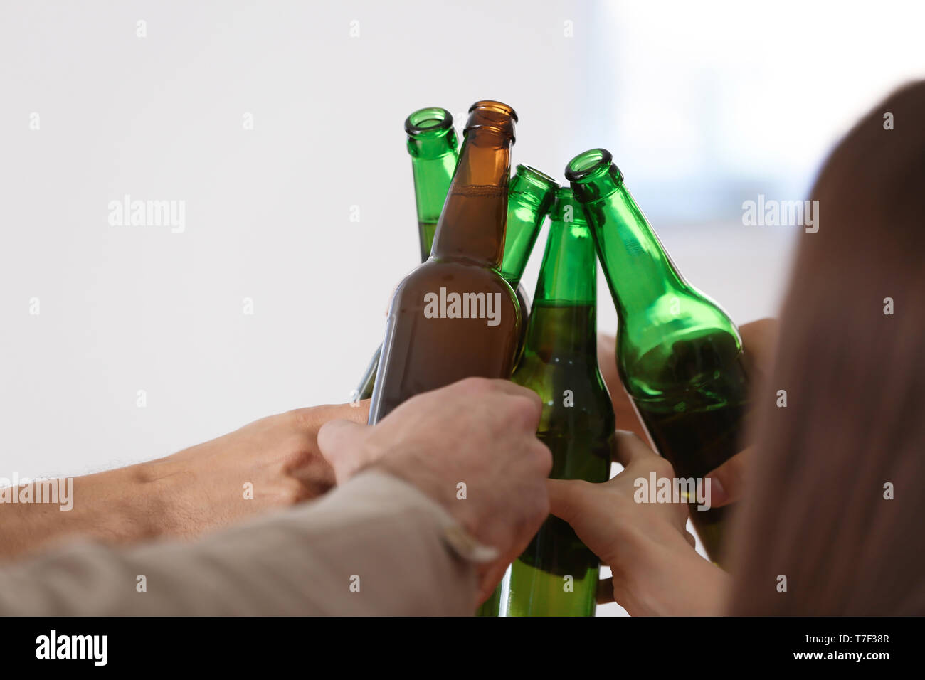 Group of friends clinking bottles with beer in bar Stock Photo - Alamy