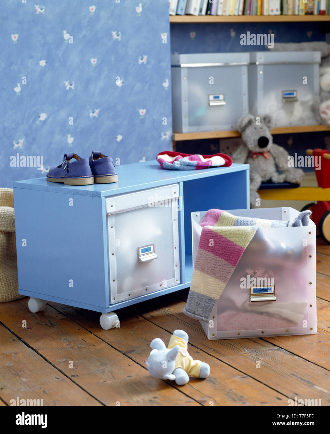 Plastic toy box beside blue cupboard on casters in play room Stock Photo