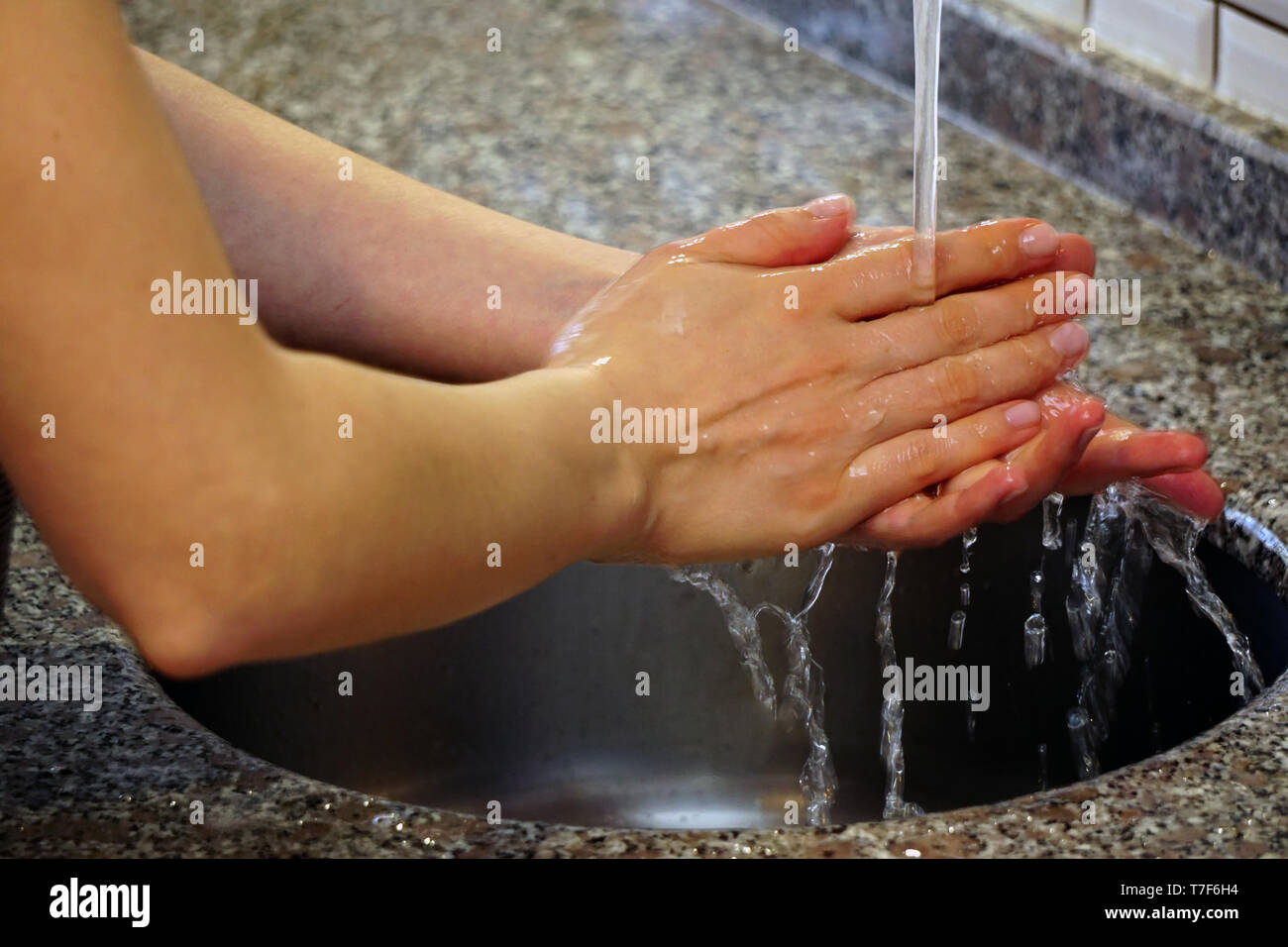 Woman washing hands with water and soap under the water in the kitchen ...