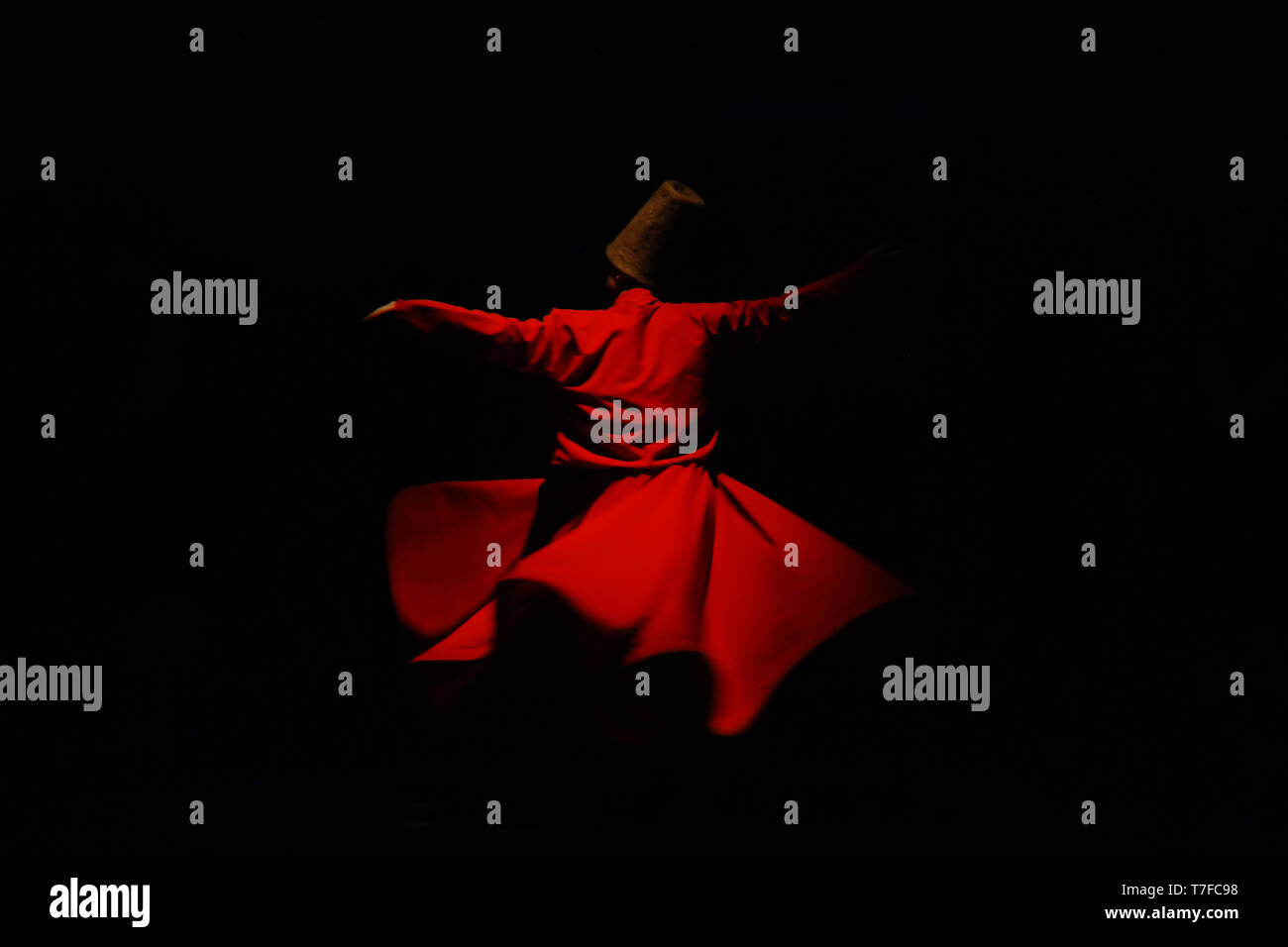 Whirling dervish in red garment on black background Stock Photo