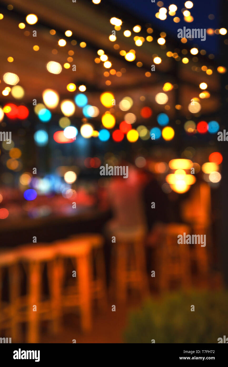 Blurred background of people sitting at restaurant, bar or night club with colorful lights bokeh. Stock Photo