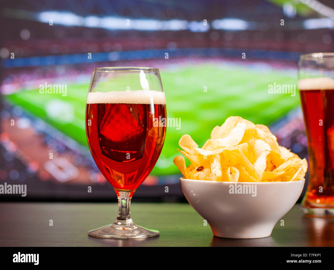Beer glasses and chips in front of tv, football at home, soccer