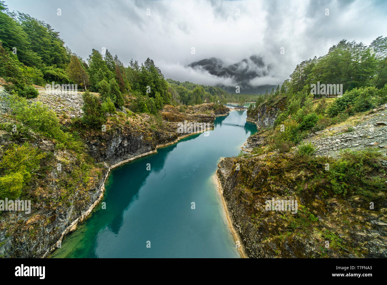 Awe hanging bridge at north Chilean Patagonia, Puelo river moves around the narrow gorge with its turquoise waters on an awe idyllic environment Stock Photo
