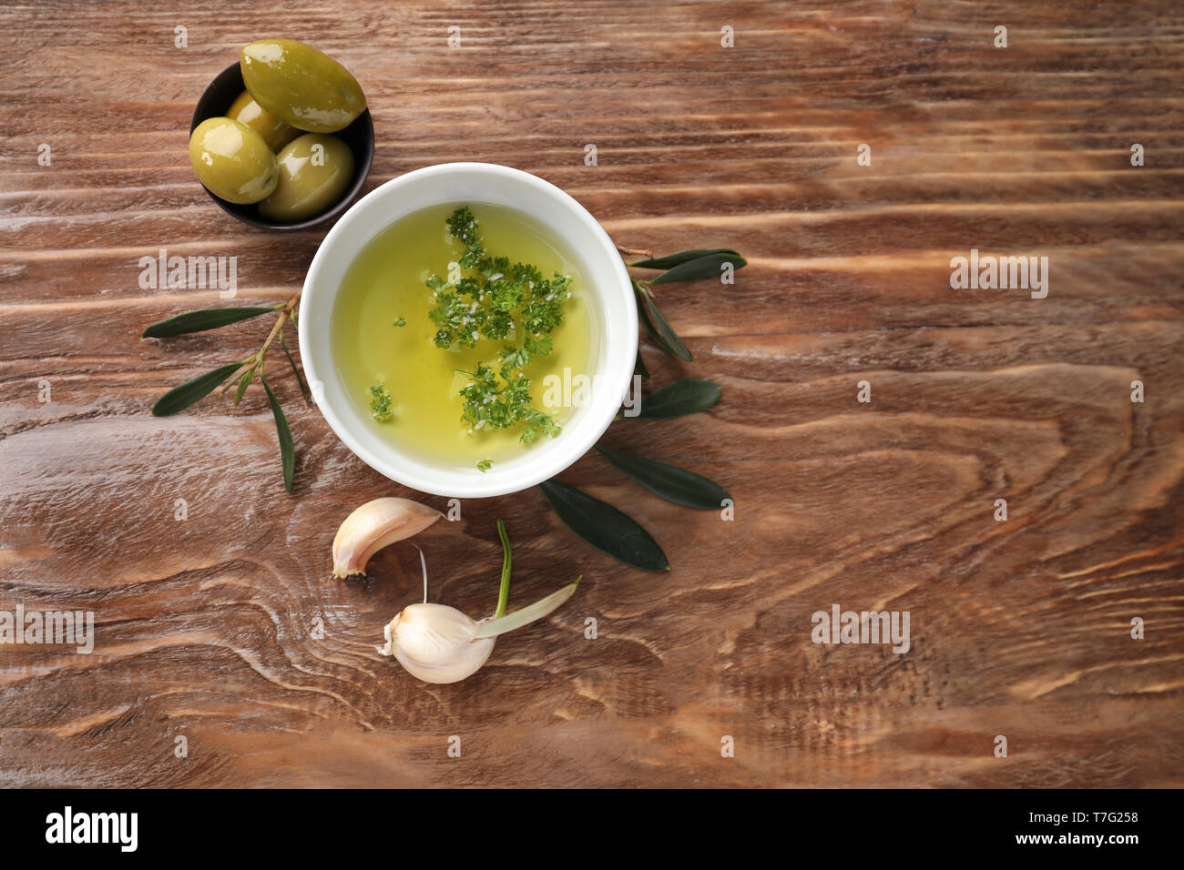 Bowls with oil and olives on wooden table Stock Photo