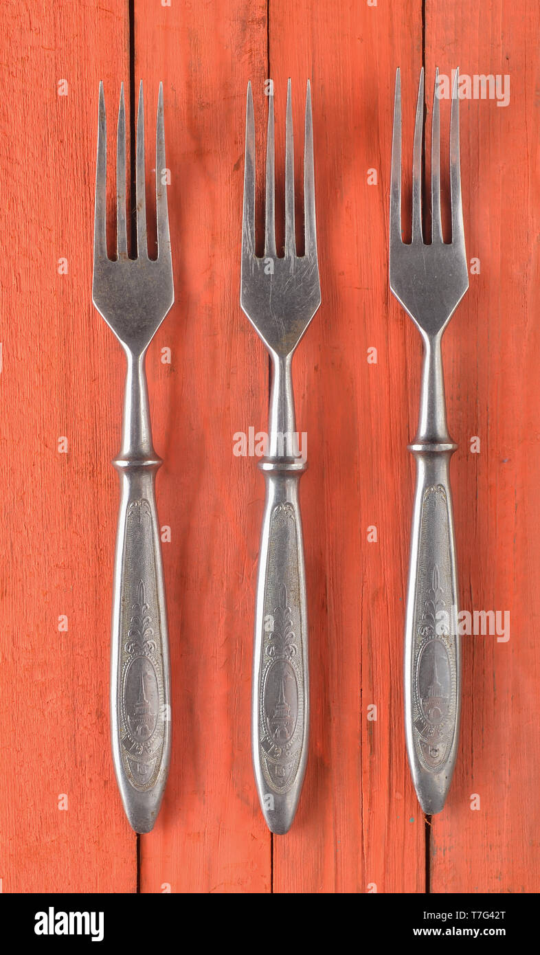 A set of forks on an orange wooden surface. Top view. Stock Photo