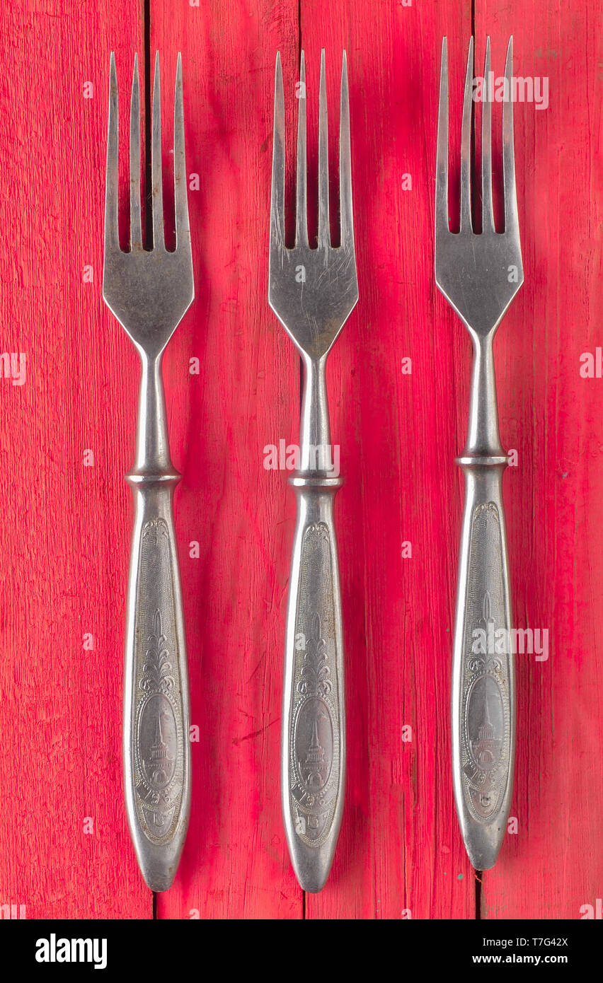 A set of forks on a red wooden surface. Top view. Stock Photo