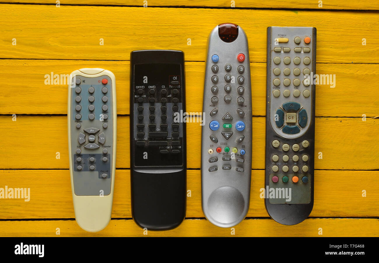 Many obsolete TV remotes on a yellow rustic wooden table. Top view Stock  Photo - Alamy