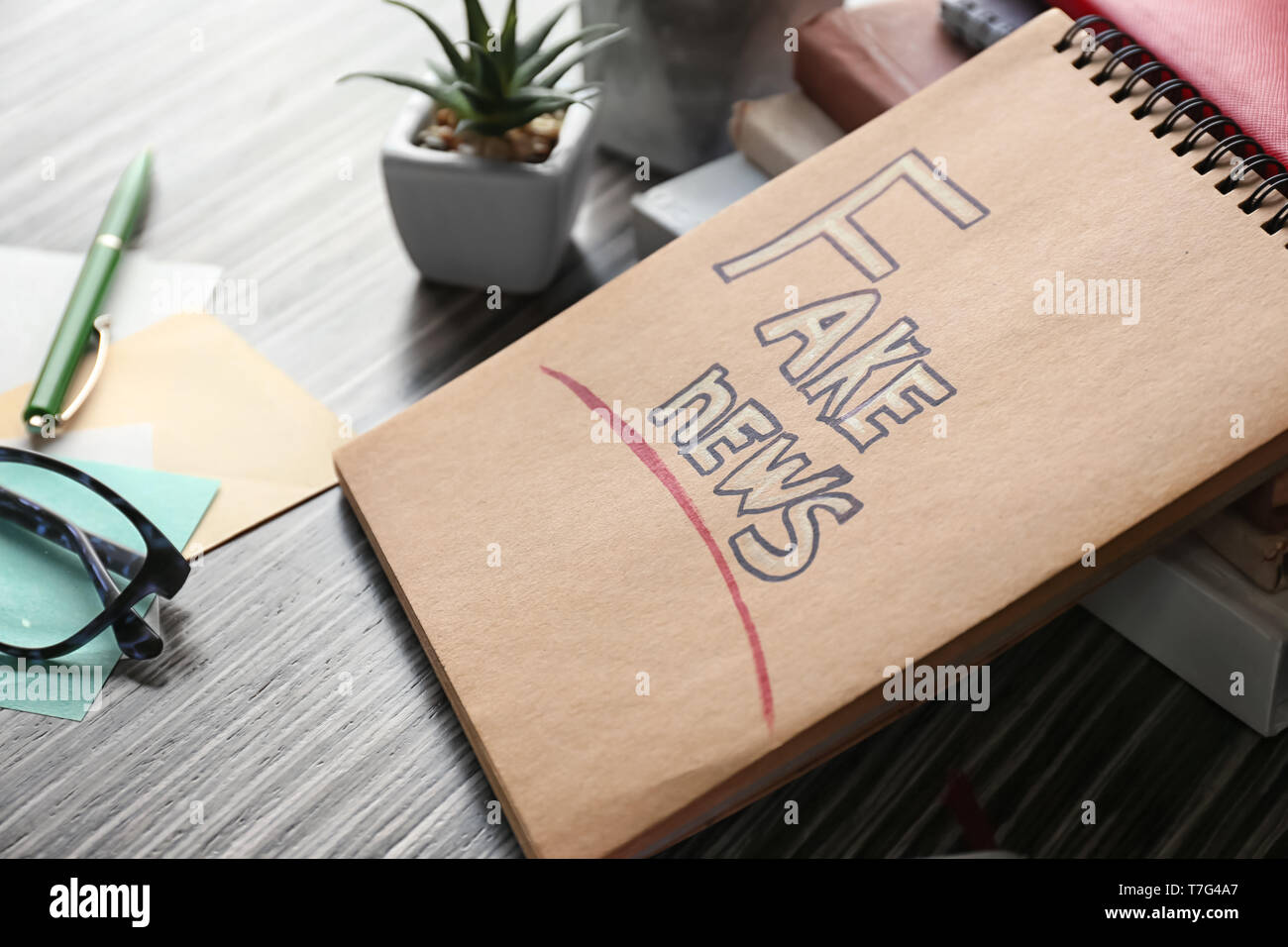 Notebook with phrase FAKE NEWS on table Stock Photo