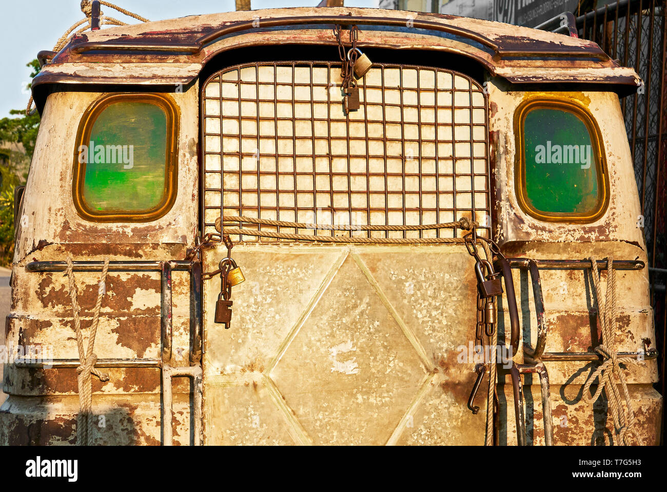 Rear of an old rusty jeepney type of delivery truck, with green windows several padlocks attached to it, parking in the streets of Iloilo, Philippines Stock Photo