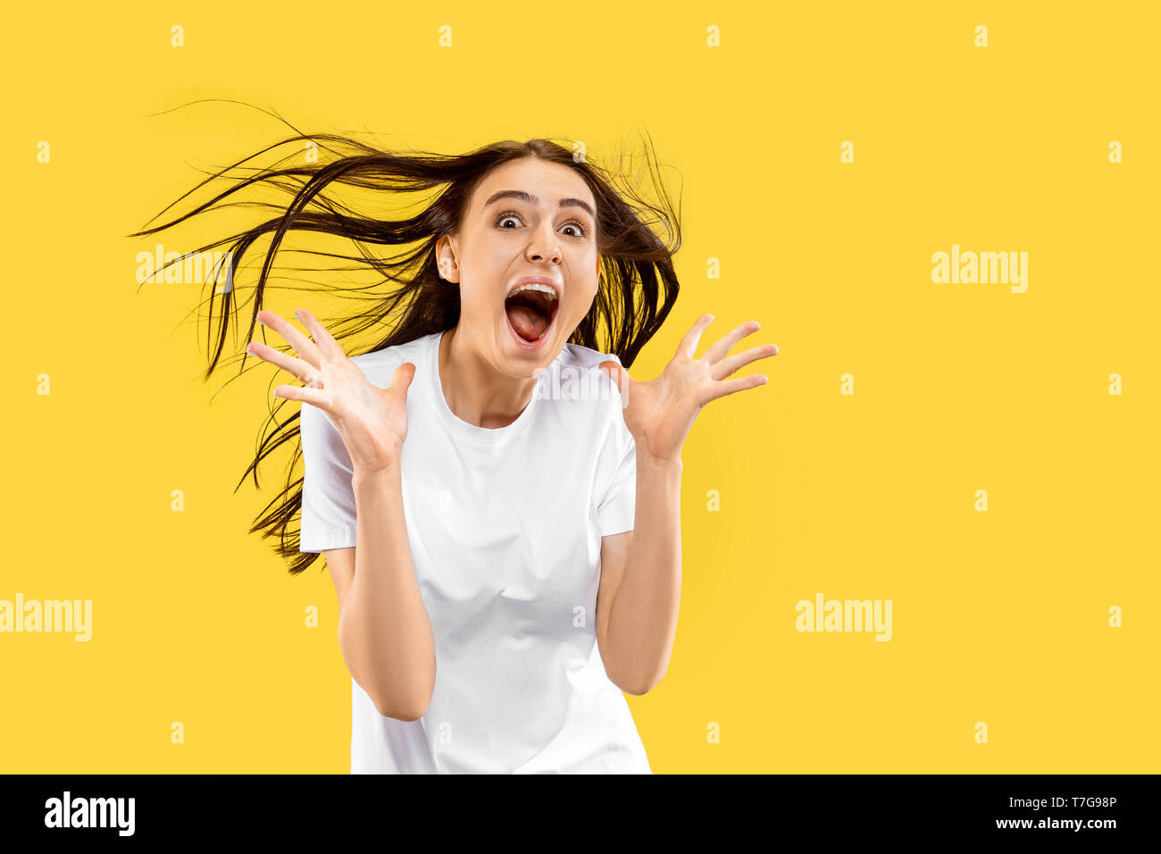 Brilliant news and sea of happieness. Beautiful female half-length portrait isolated on yellow studio background. Young smiling woman. Negative space. Facial expression, human emotions concept. Stock Photo