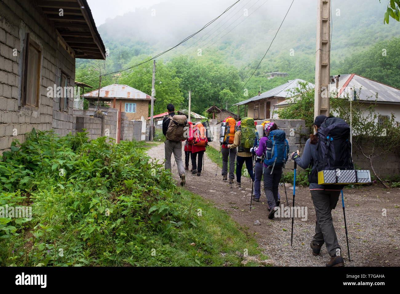 A group of hiker is passing through rural area in the north of Iran. Jungle sight is in the background. Stock Photo