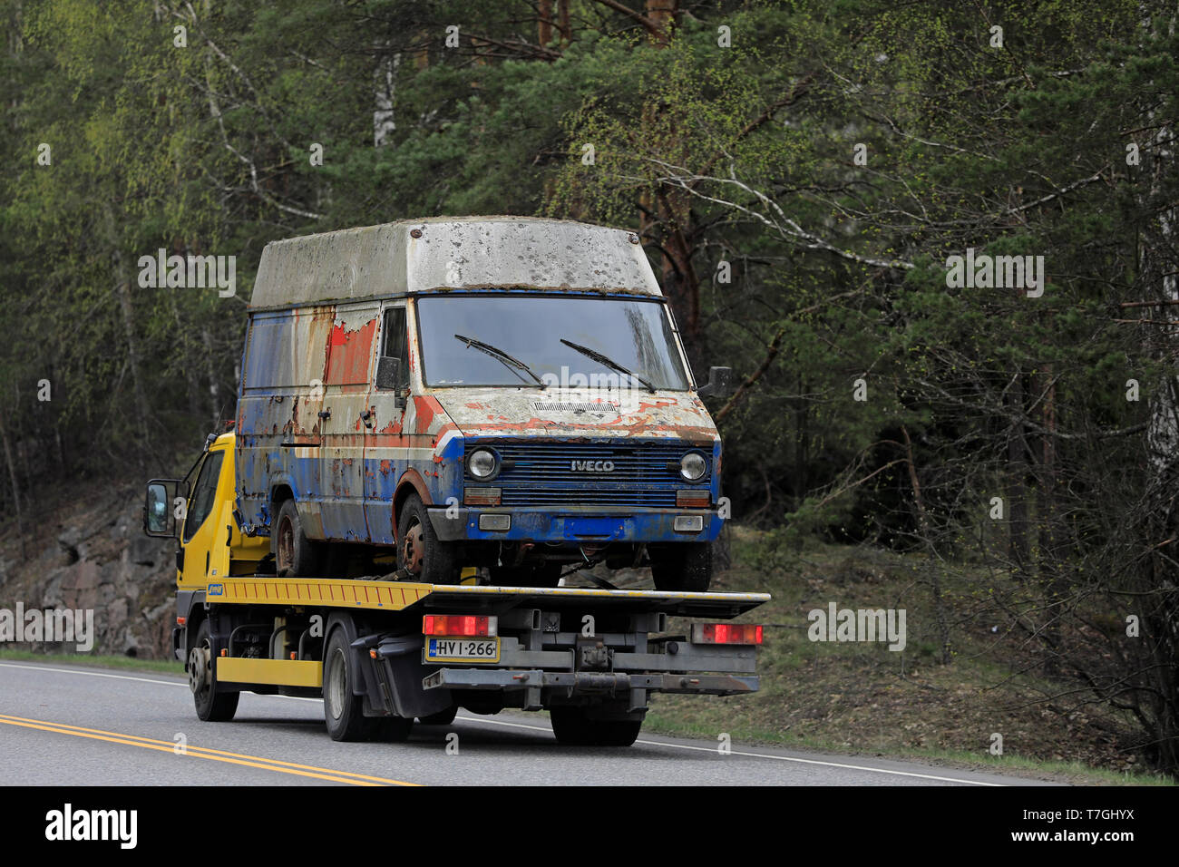 Salo, Finland - April 26, 2019: Yellow Mitsubishi Fuso Canter tow truck carries an old van along highway on a day of spring, rear view. Stock Photo
