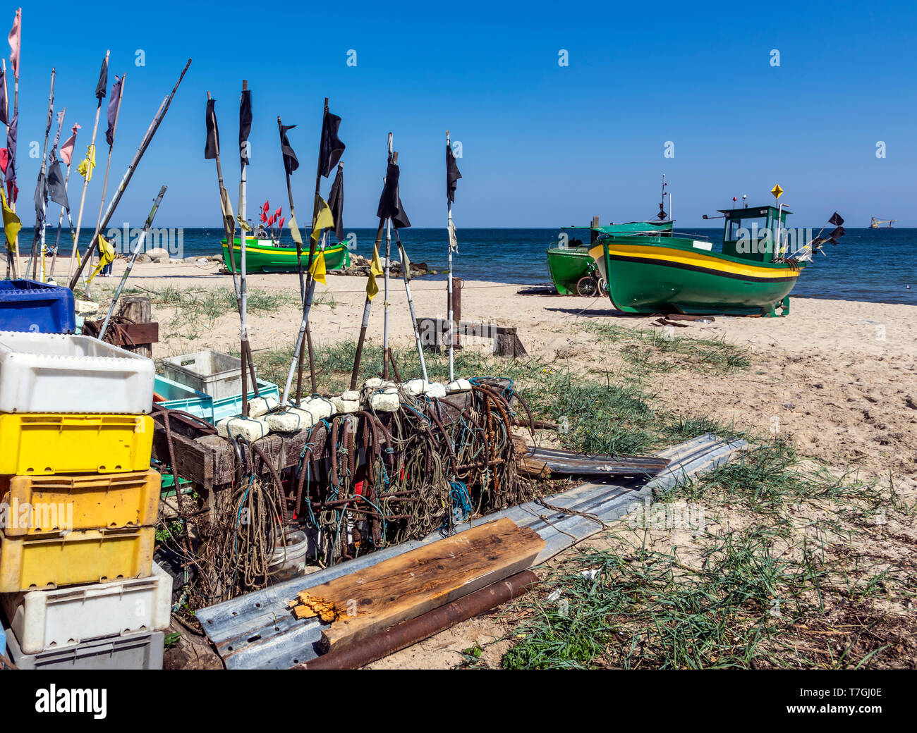 Small, green fishing boat resting on shore. Beach near Gdynia, Poland. In foreground old fishing equipment Stock Photo